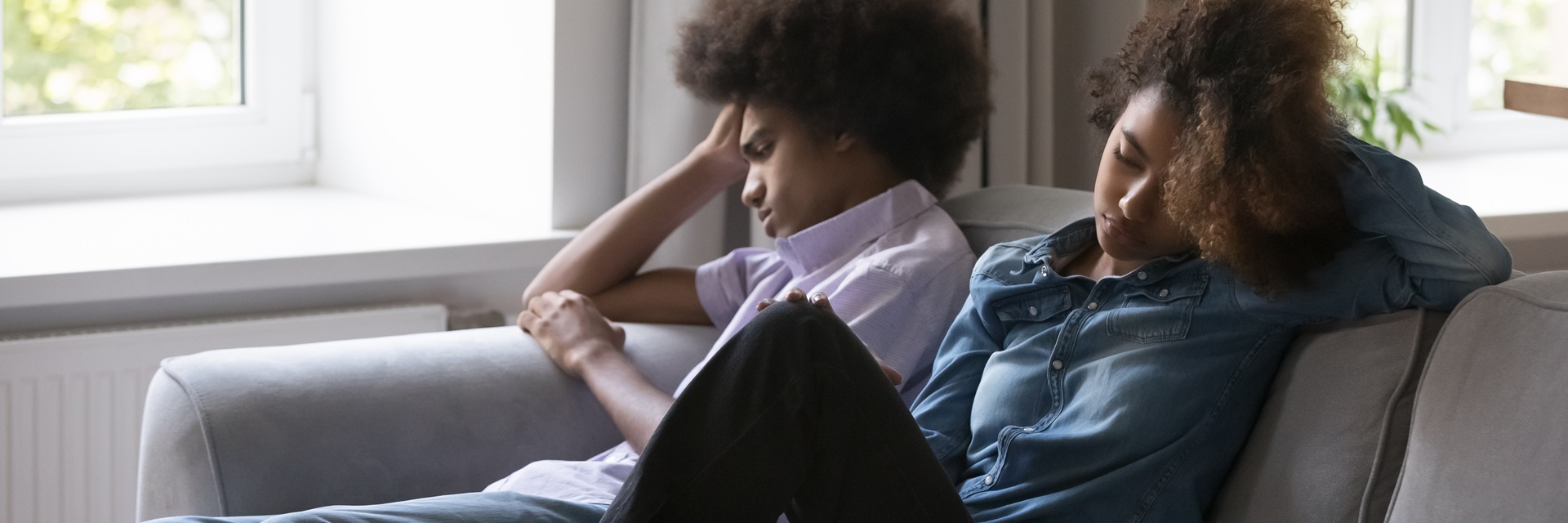 two teens in a troubled relationship sitting on a couch together